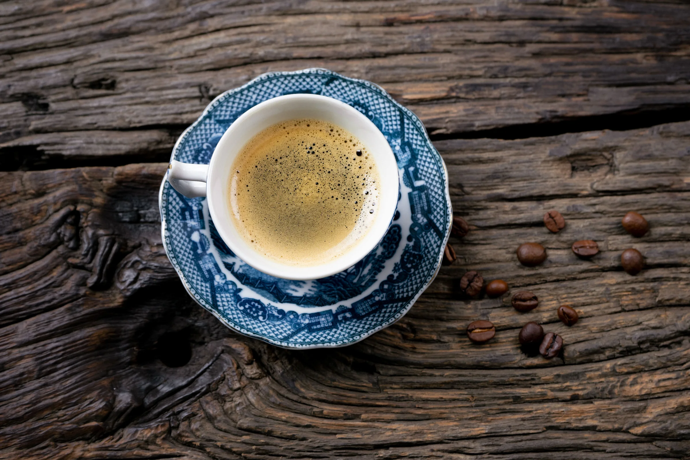 An espresso in a blue patterned cup on a dark rustic wooden table