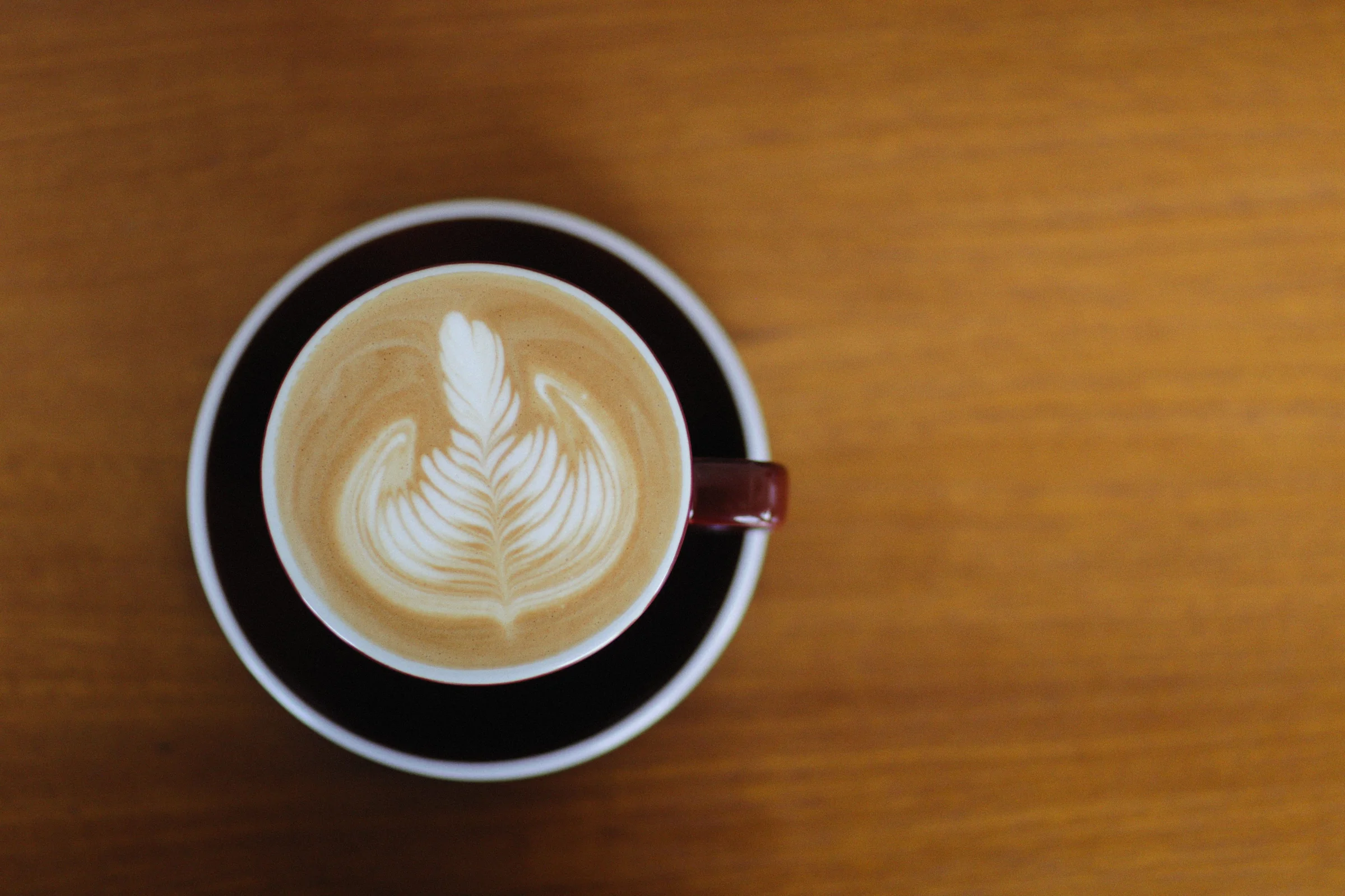 A cappuccino with latte art seen from above on warm wood