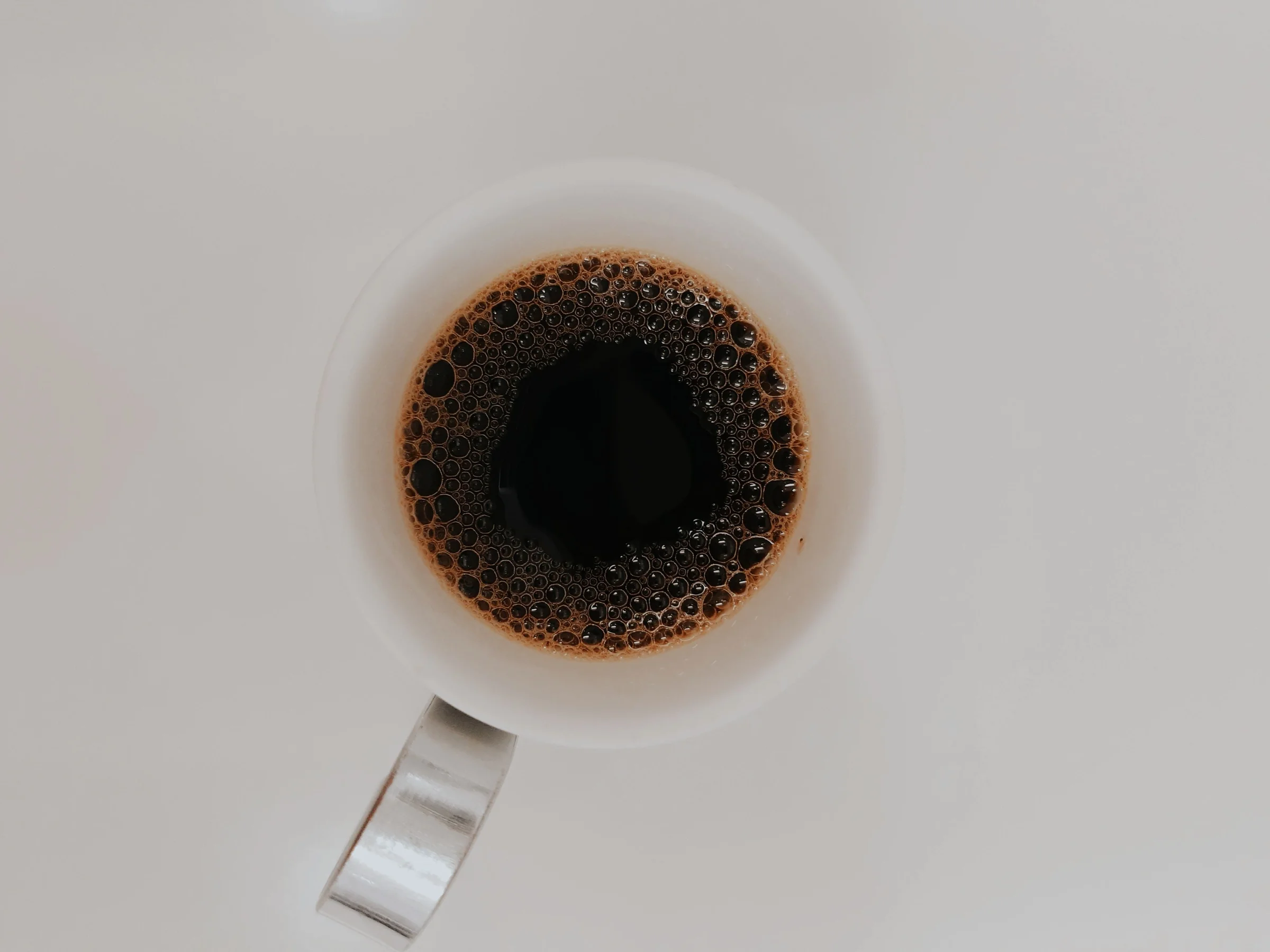 A cup of black coffee in a white cup, seen from above