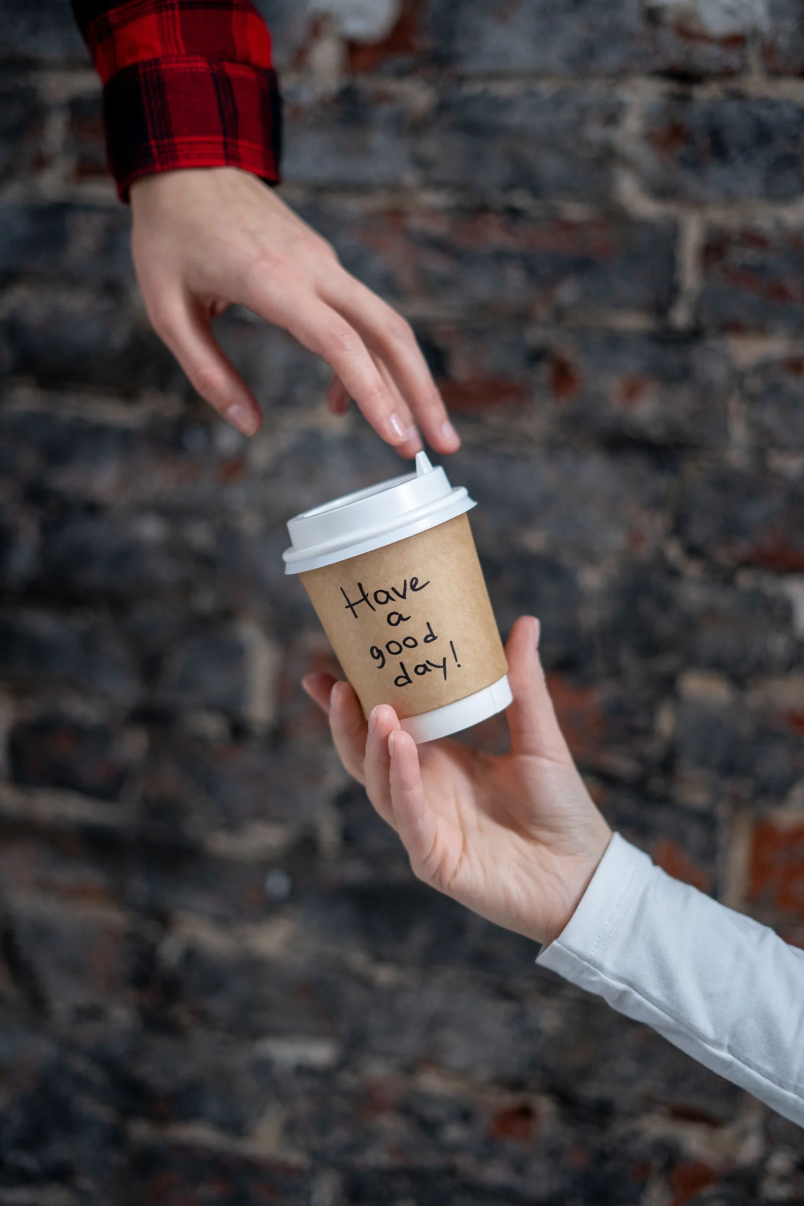 Walk up and order: a paper coffee cup handed from one person to another