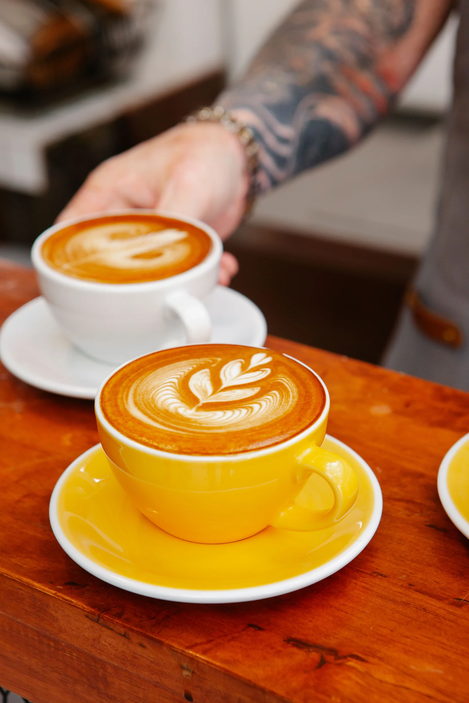 A latte with leaf art set down on a wooden counter